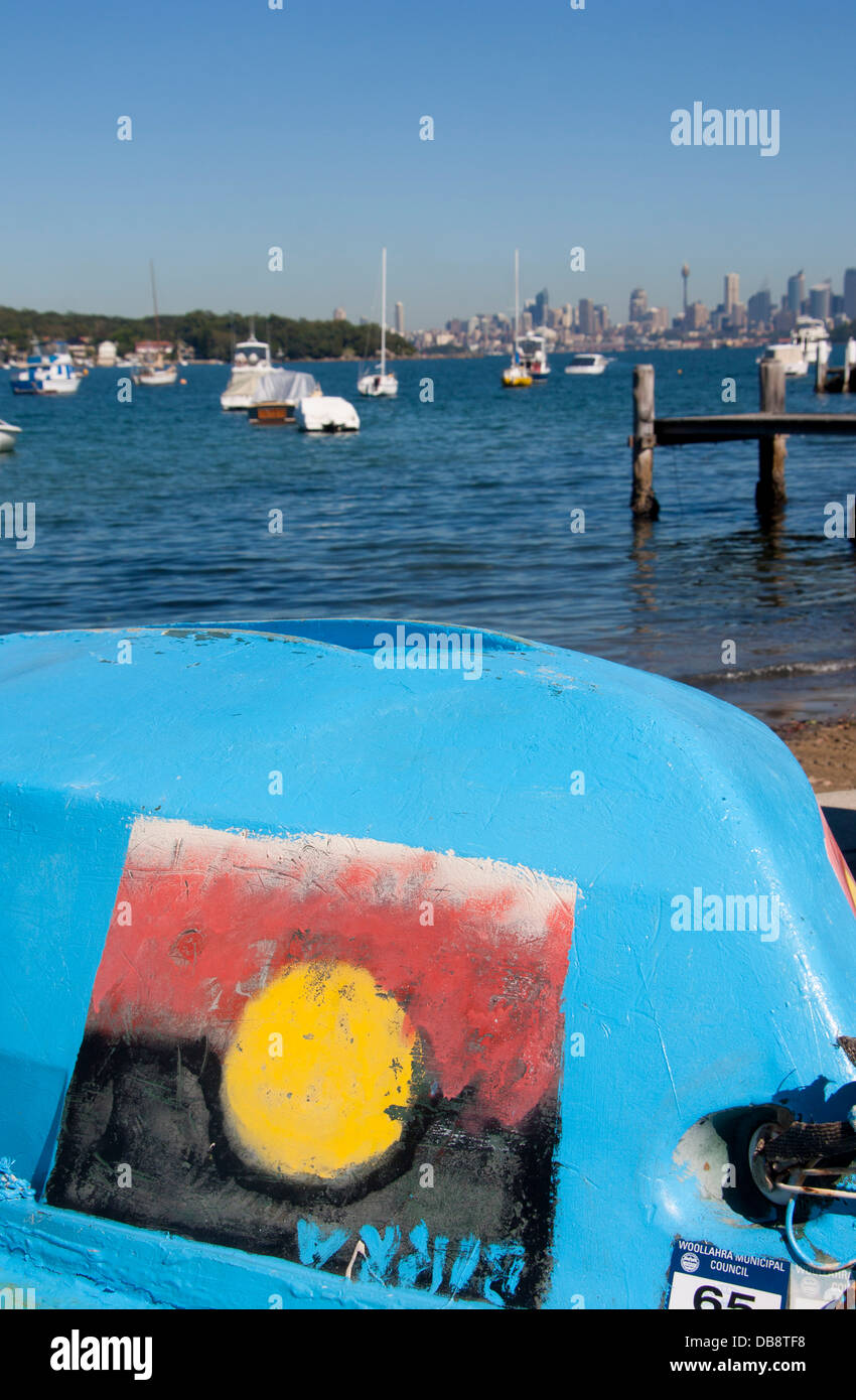 Watsons Bay boat on beach with Aboriginal flag painted on side city skyline in distance Sydney New South Wales (NSW) Australia Stock Photo