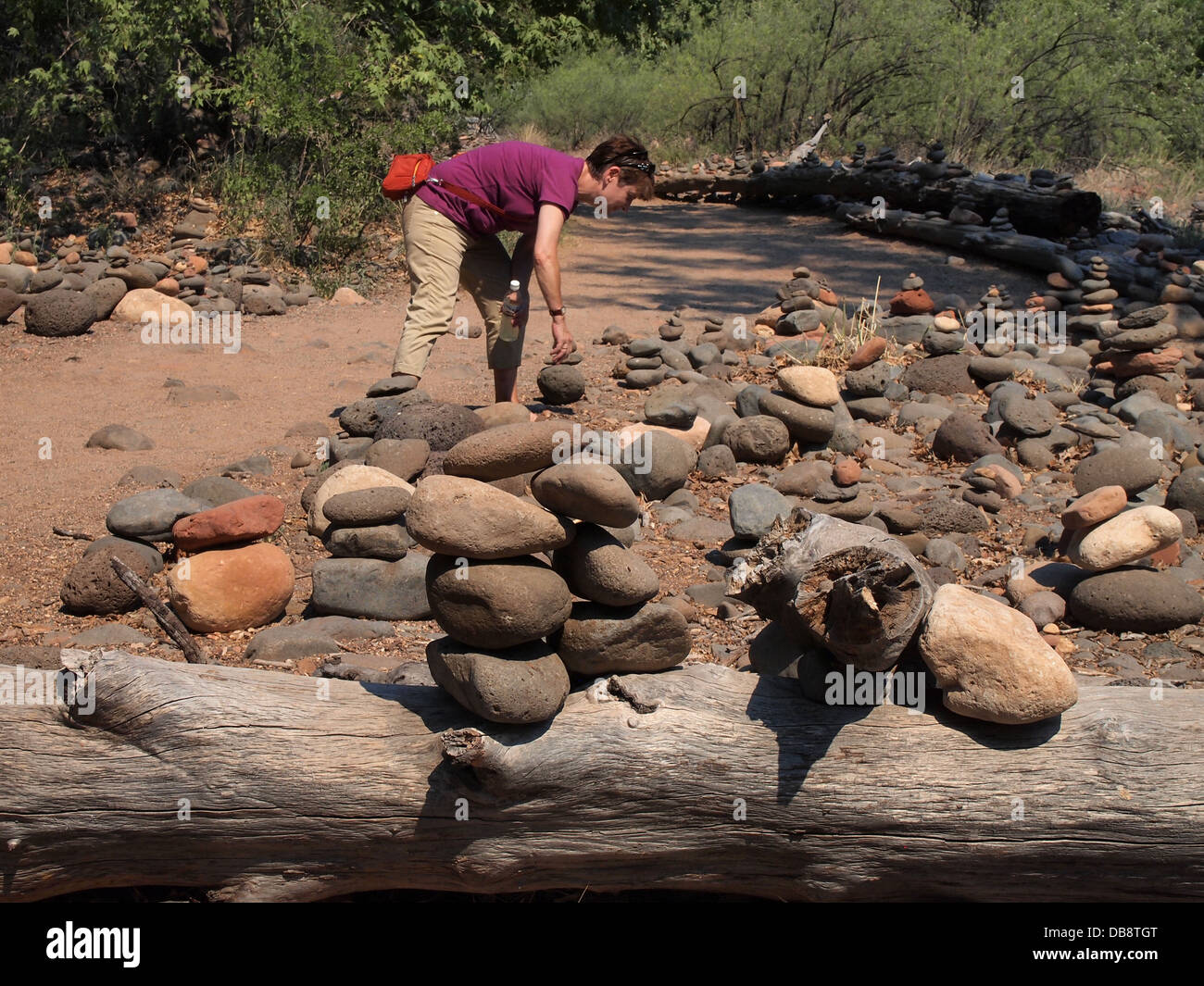 Woman stacking stones along a trail to Cathedral Rock, a magnetic (feminine) energy vortex, in Sedona, Arizona, USA Stock Photo