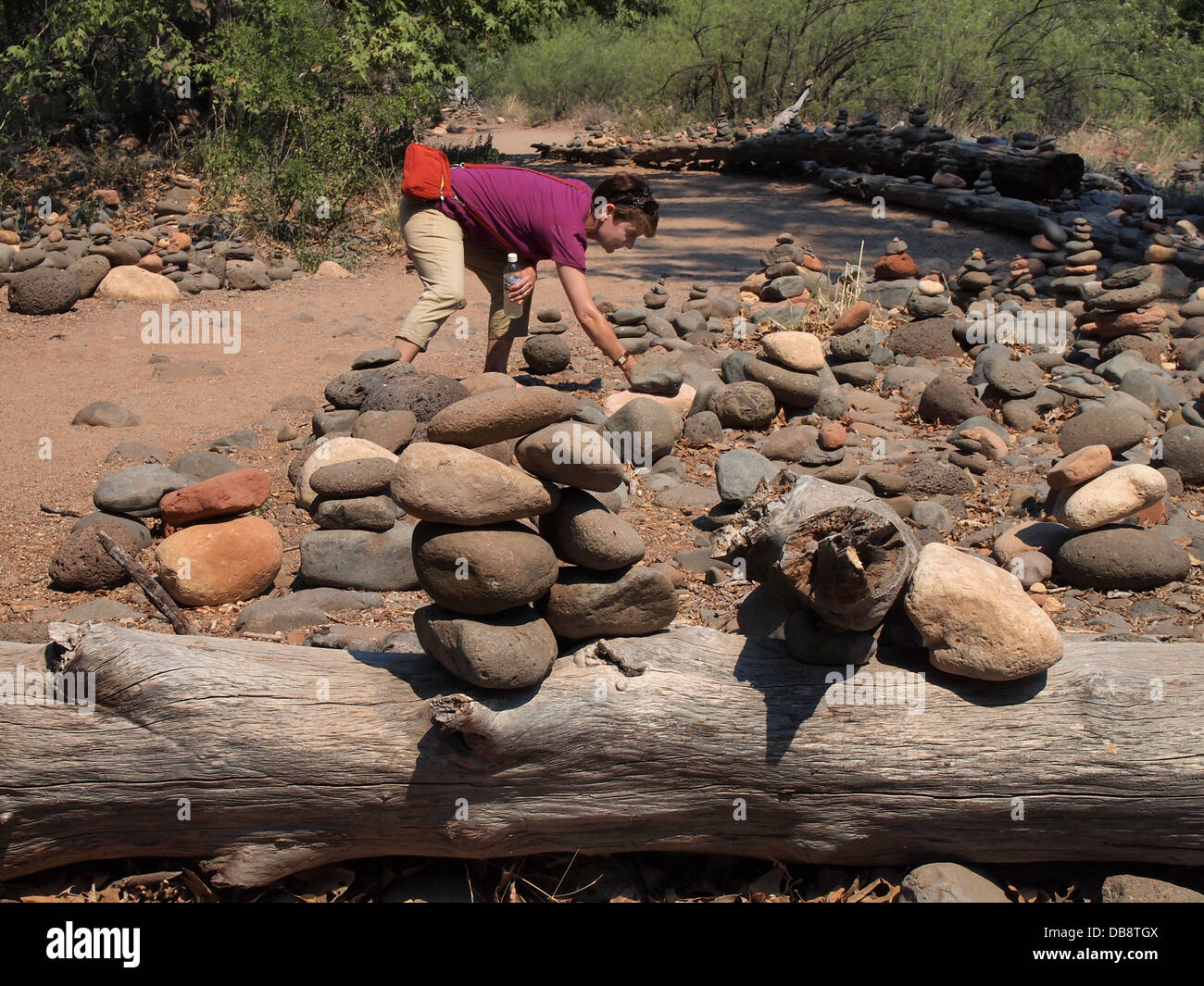 Woman stacking stones along a trail to Cathedral Rock, a magnetic (feminine) energy vortex, in Sedona, Arizona, USA Stock Photo