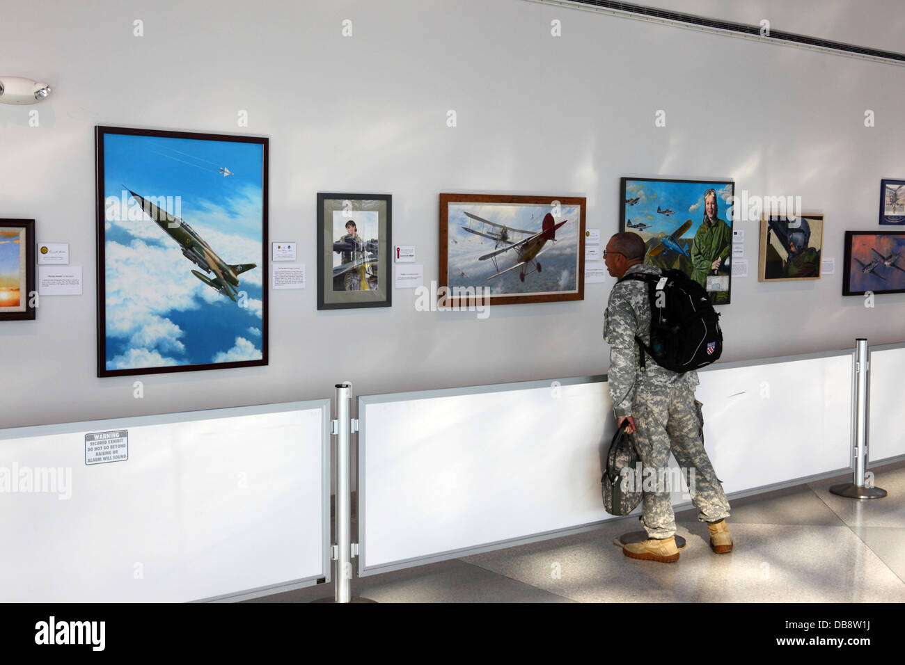 US Army soldier looking at art exhibition by American Society of Aviation Artists at Baltimore–Washington International Airport ( BWI ), Maryland, USA Stock Photo