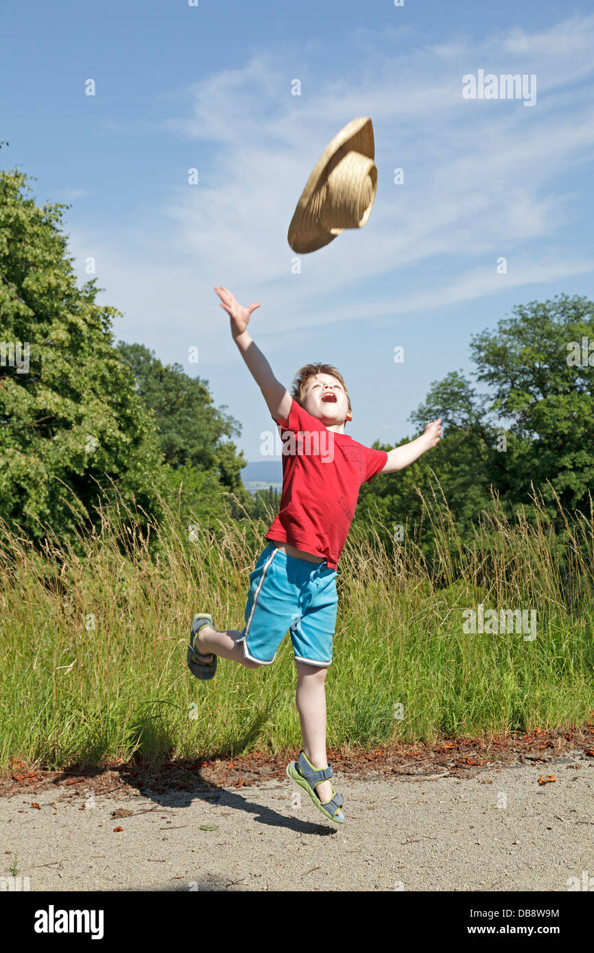 young boy throwing his straw hat into the air Stock Photo