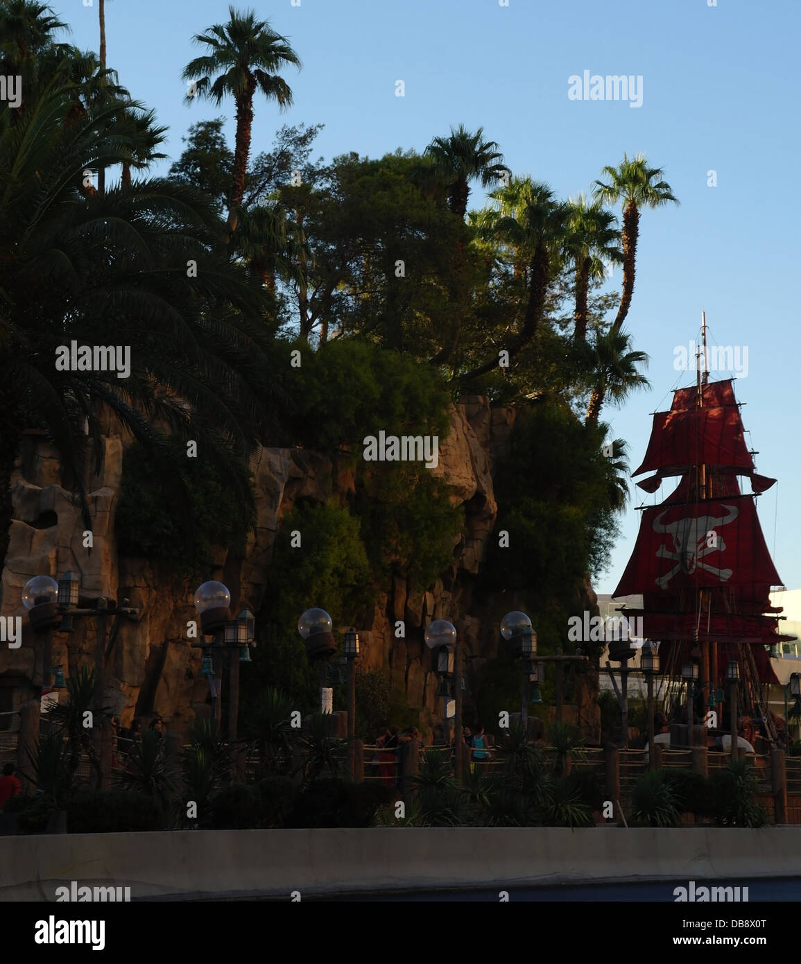 Blue sky evening portrait Bull Pirate Ship below cliff with palm trees, Sirens Cove, Treasure Island, Las Vegas Strip Stock Photo