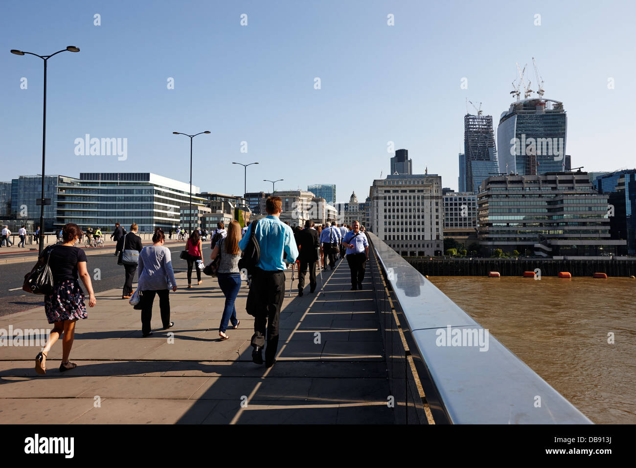 commuters and city workers cross london bridge over the river thames in the morning central London England UK Stock Photo
