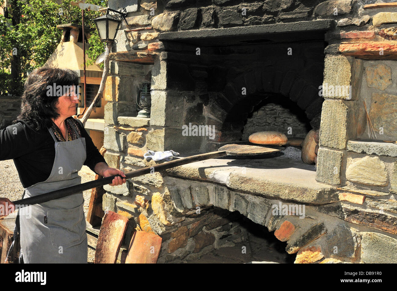 Greek woman baking bread loaves or flatbread in a traditional Greek