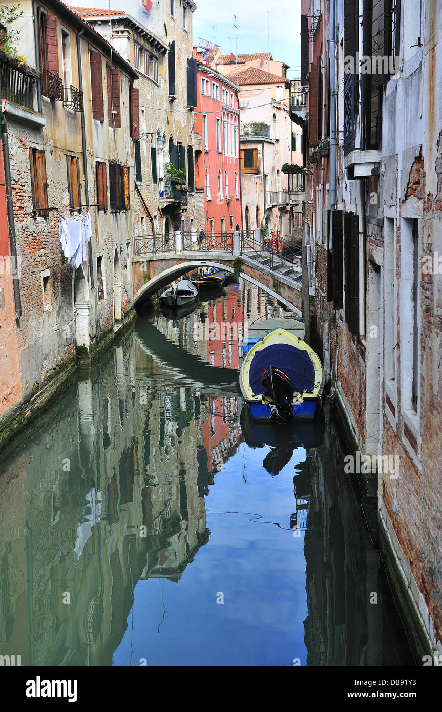 Reflections in water of a typical small canal in the centre of Venice ...