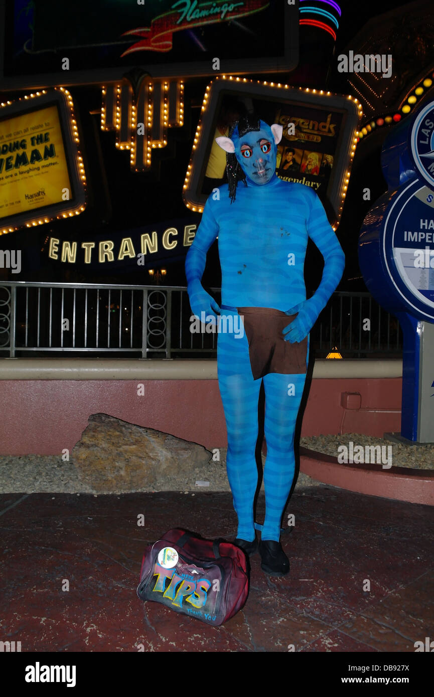Flashlight night portrait street entertainer dressed as blue Avatar Na'vi, towards neon Harrah's Sign, Las Vegas Strip, Nevada Stock Photo