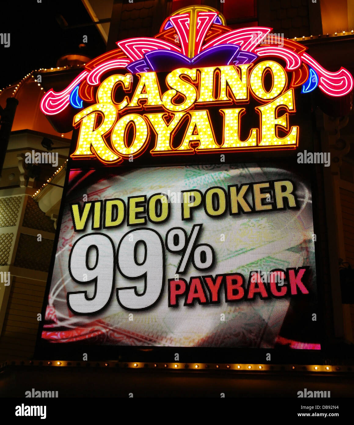 Night portrait electronic billboard 'Video Poker 99% Payback' below yellow pink neon sign, Casino Royale, The Strip, Las Vegas Stock Photo