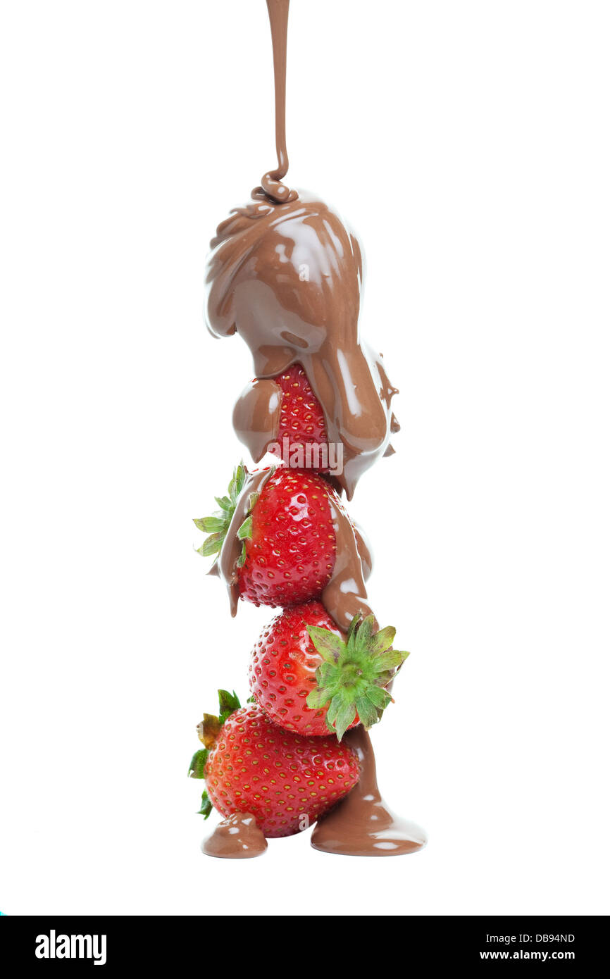Milk chocolate being poured over a stack of strawberries. Stock Photo