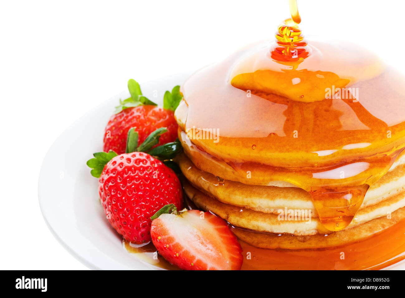Pancakes and strawberry with heavy amount of maple syrup poured on top Stock Photo