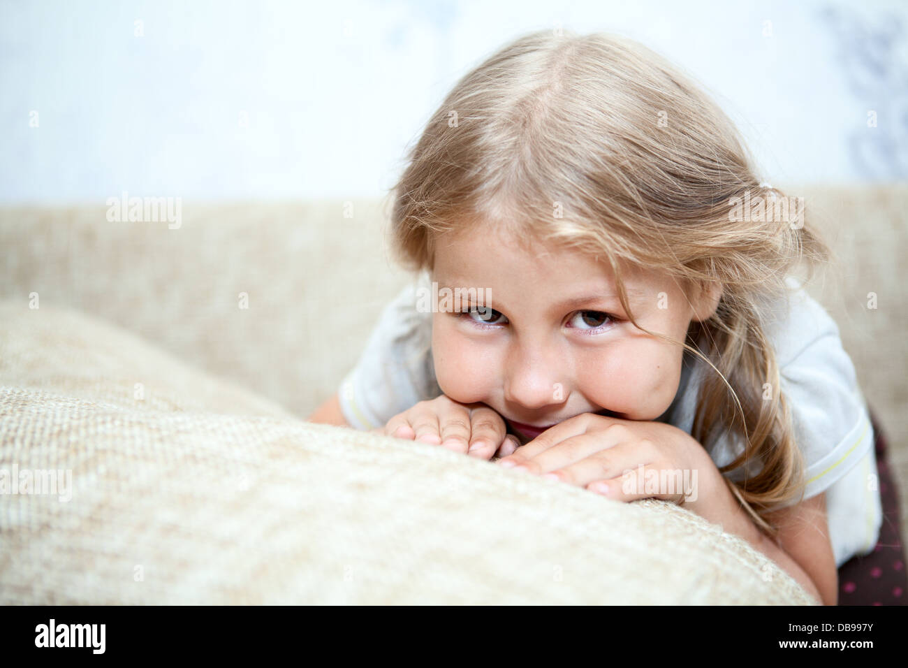 Sly Caucasian girl hiding her face in sofa pillows Stock Photo - Alamy