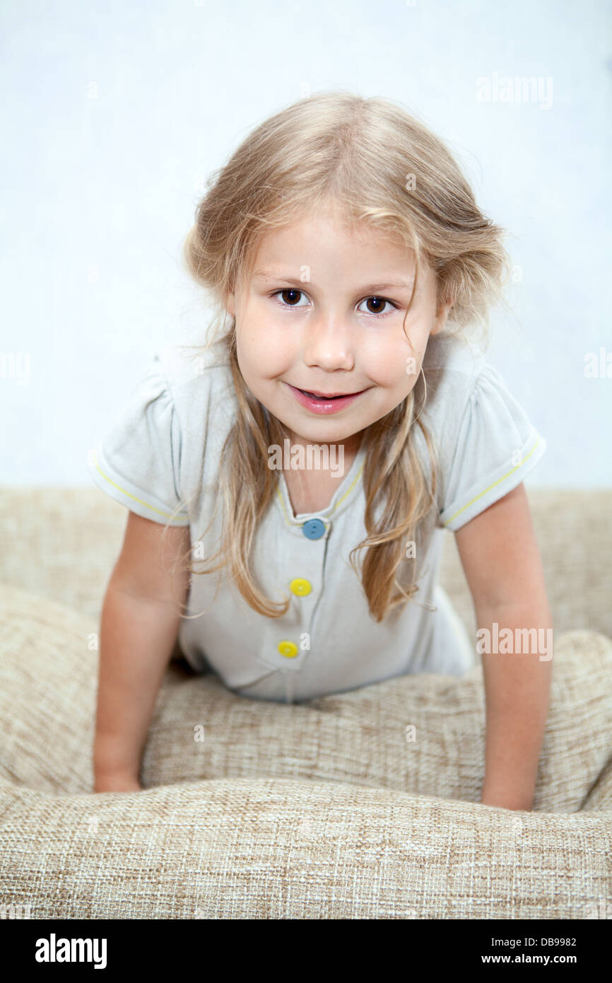 Playful Caucasian girl sitting on sofa pillows Stock Photo - Alamy