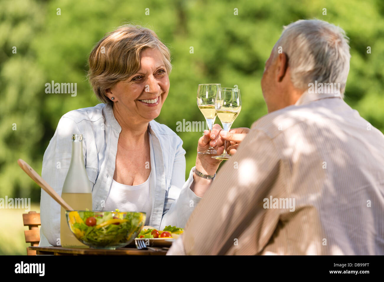 Happy senior citizens clinking glasses in garden Stock Photo