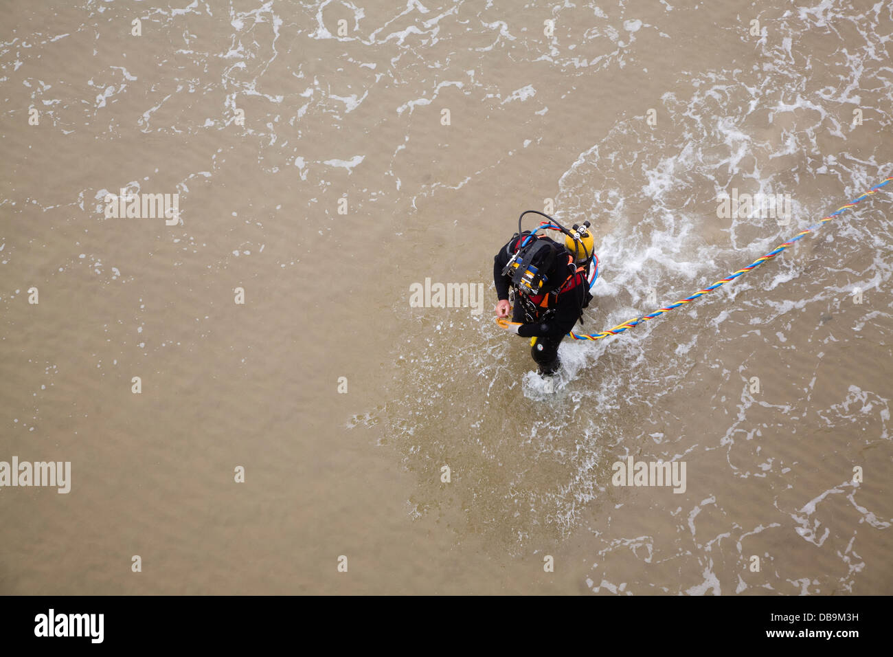 Diver walking into sea in full equipment UK Stock Photo