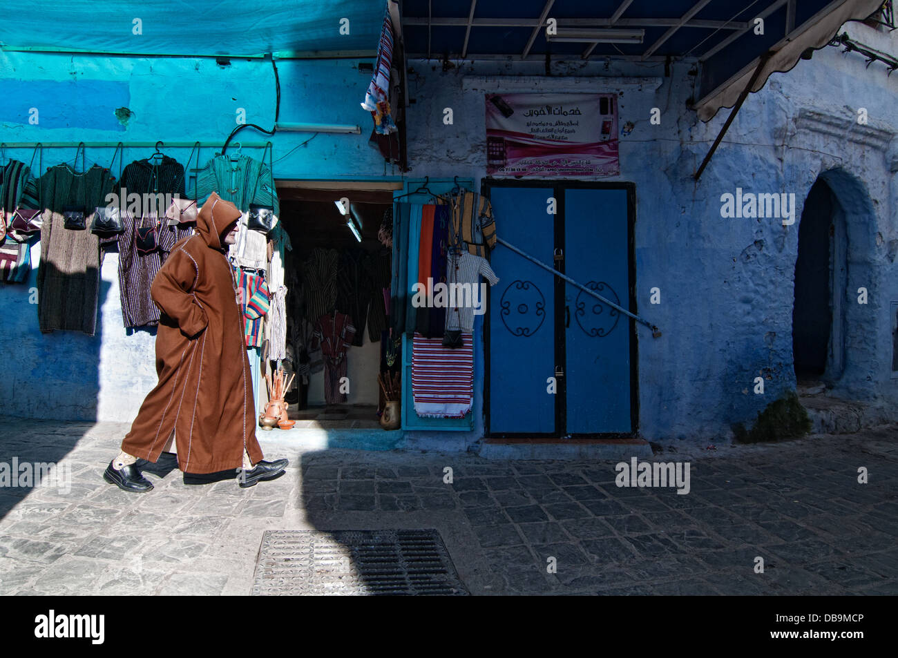 Man passing by a textile shop in the medina. Chefchaouen, Rif region, Morocco Stock Photo