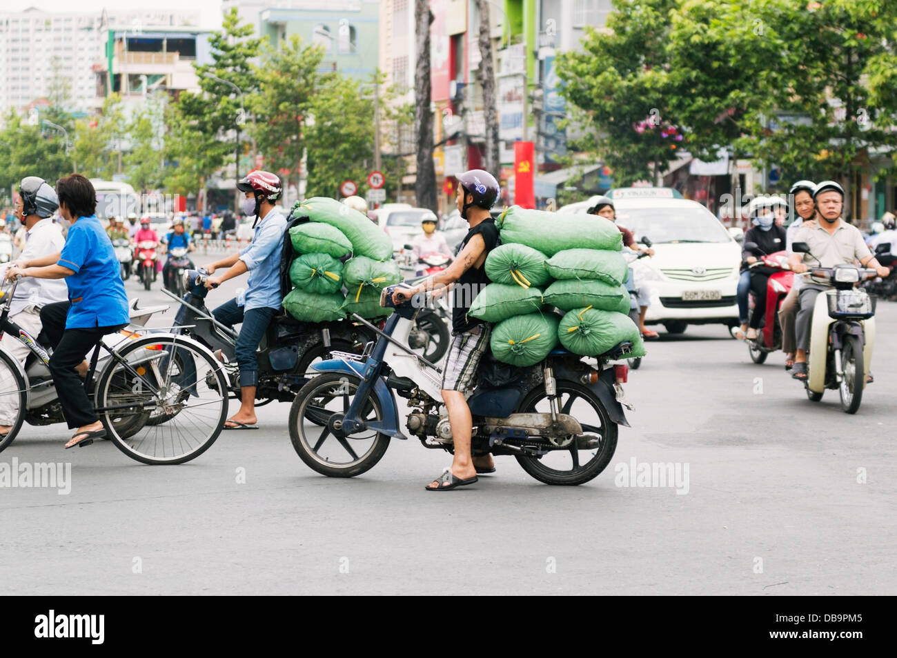 Ho Chi Minh City (Saigon), Vietnam - heavily loaded scooters being used to transport goods in traffic Stock Photo