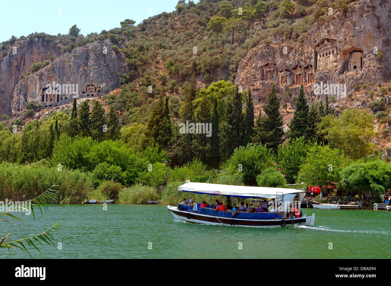 Rock tombs above the Dalyan river and tourist boat at Dalyan, Ortaca, Mugla, Turkey. Stock Photo