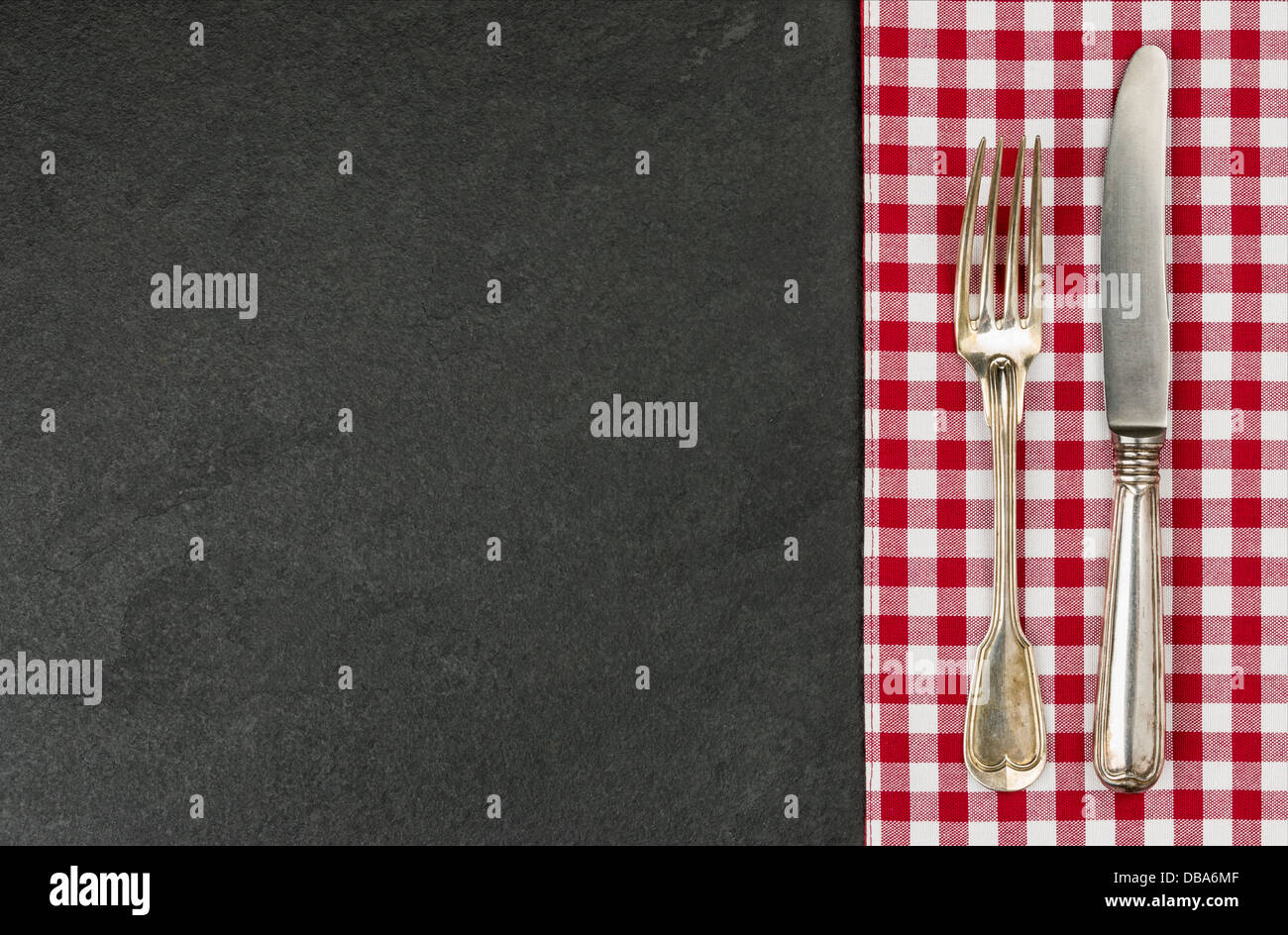 Silverware on a slate plate with a red checkered tablecloth Stock Photo