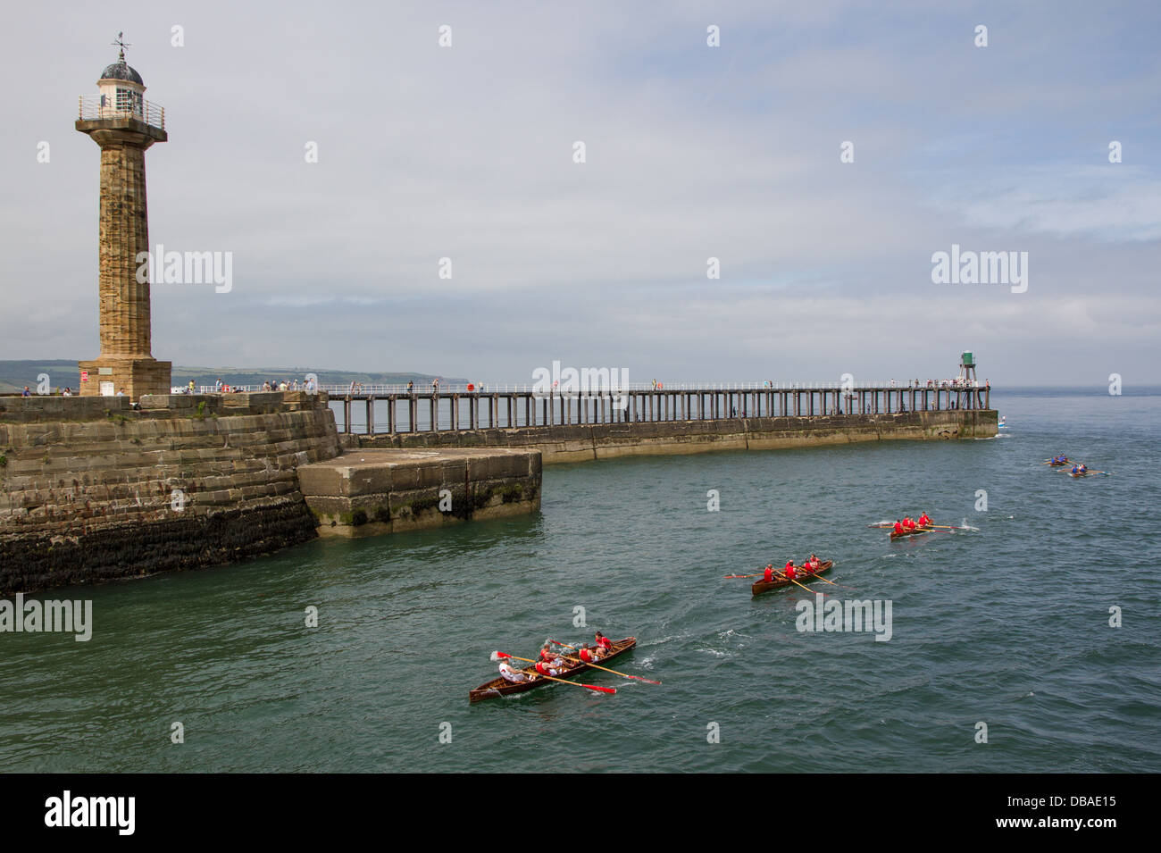 Rowing boat race in Whitby Harbour with the West Pier and lighthouses in background Stock Photo