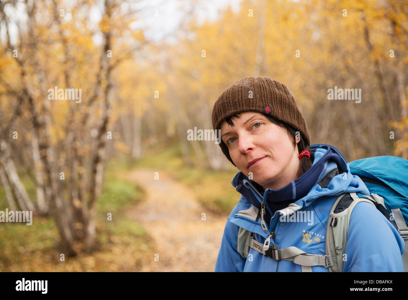 Portrait of female hiker in yellow Autumn birch forest along Kungsleden trail, near Abisko, Lappland, Sweden Stock Photo
