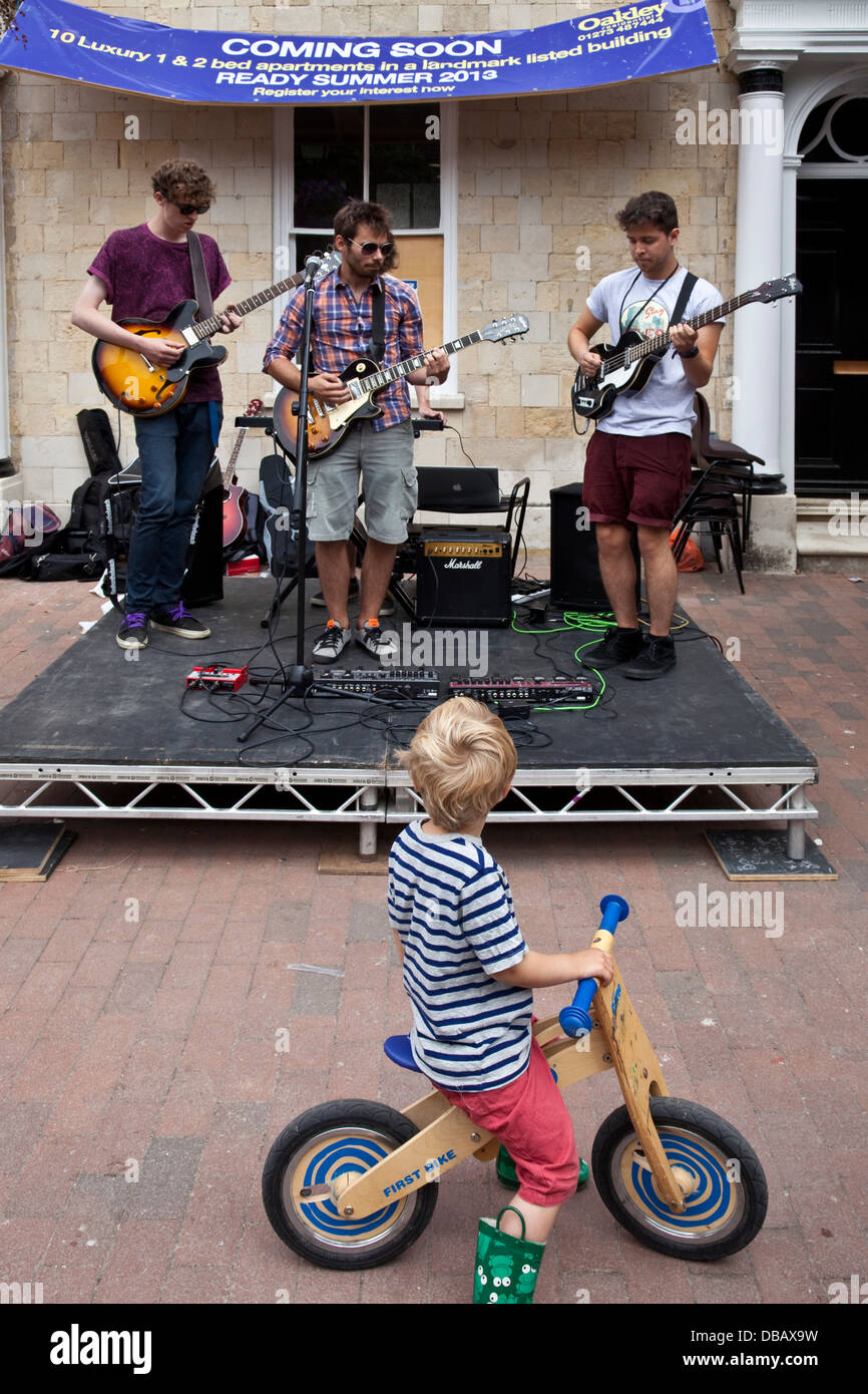 A boy on his bicycle watches local band Lemon Soul perform in Lewes town centre during The GOTR Festival, Lewes, Sussex, England Stock Photo