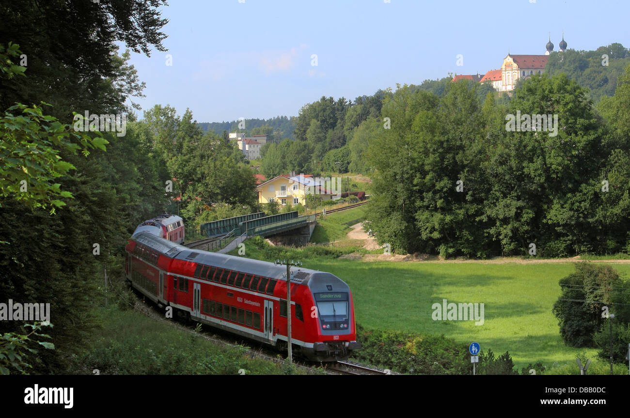 roter Zug in der Landschaft unter der Klosterkirche Baumburg red train in green landscape below baroque church Stock Photo