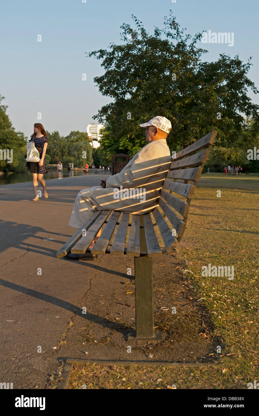 Man sitting on a bench in a park, watching a girl walk by. Stock Photo