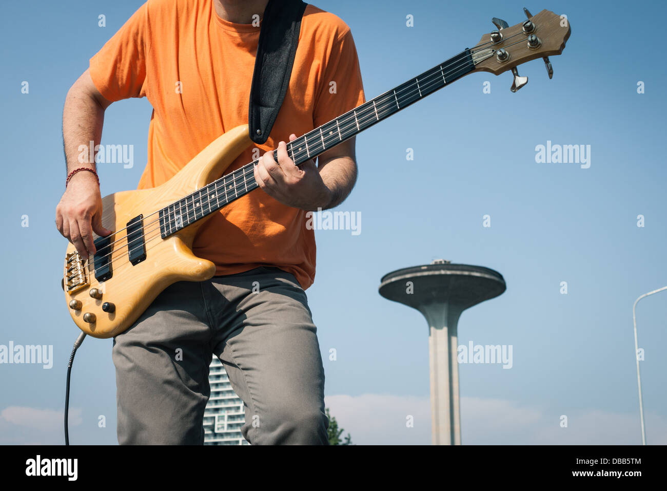 Detail of a young musician playing bass guitar in the street Stock