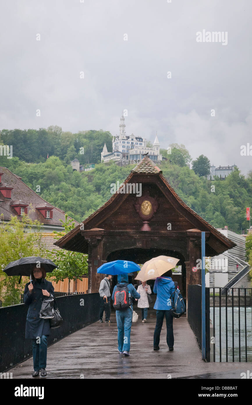 People walk across the Chapel bridge in rainy day, Lucerne, north-central Switzerland, Europe Stock Photo
