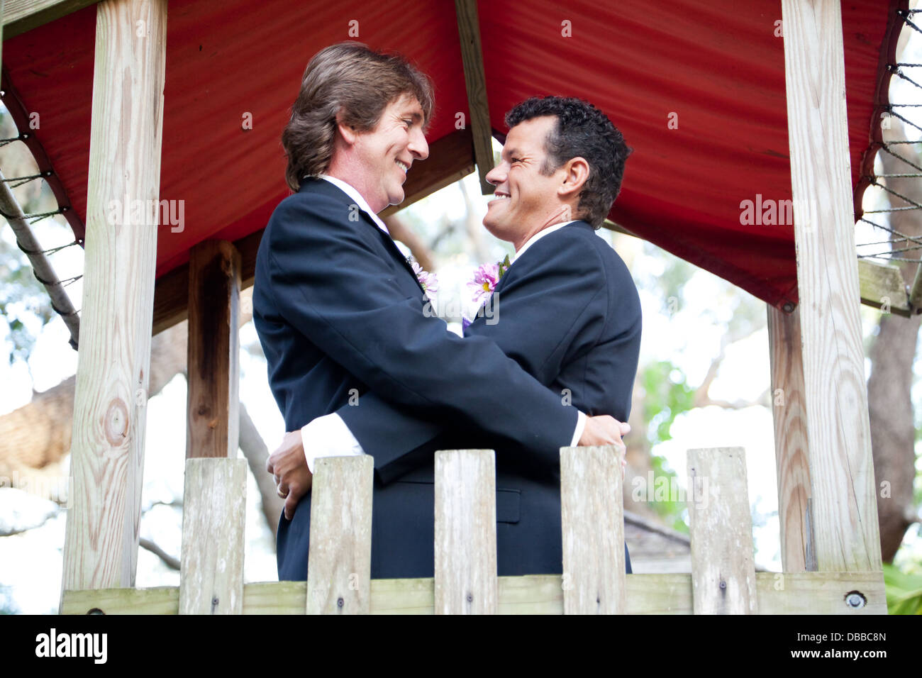 Happy gay couple getting married on the playground of a park.  Stock Photo