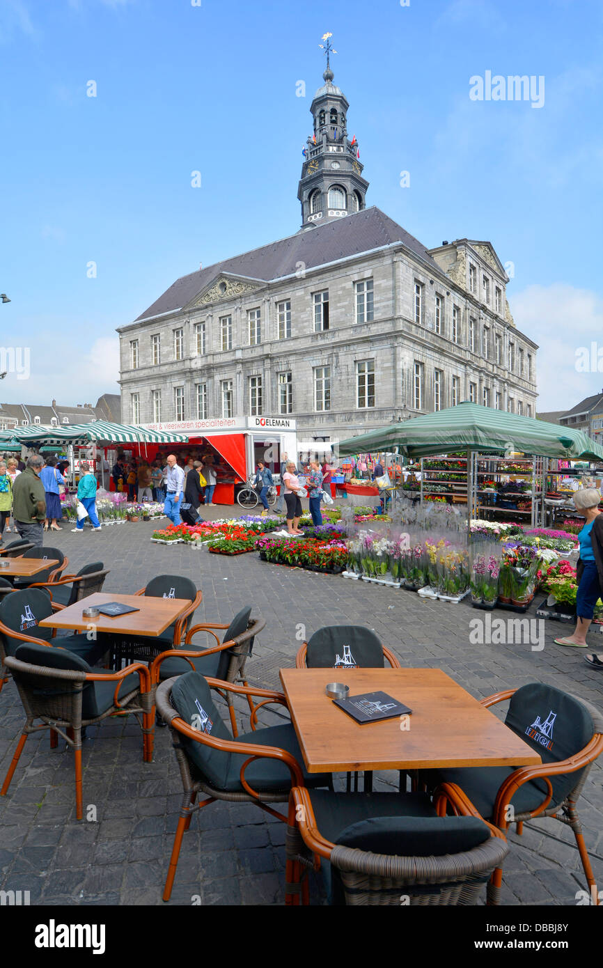 Maastricht cafe bar tables outdoors around  Market Square with stalls selling flowers & plants Town Hall building beyond Limburg Netherlands Stock Photo
