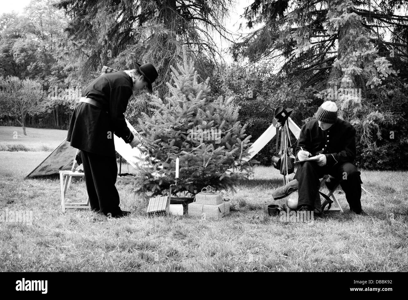 Young Civil War soldier reenactors at Christmas time decorating a Christmas tree with garland and writing letter home Stock Photo