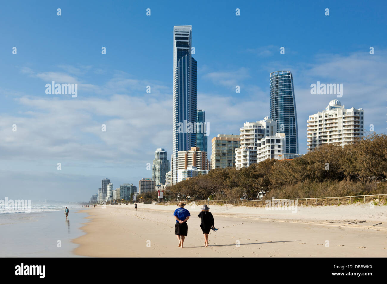 Couple walking along beach with city skyline in background. Surfers Paradise, Gold Coast, Queensland, Australia Stock Photo