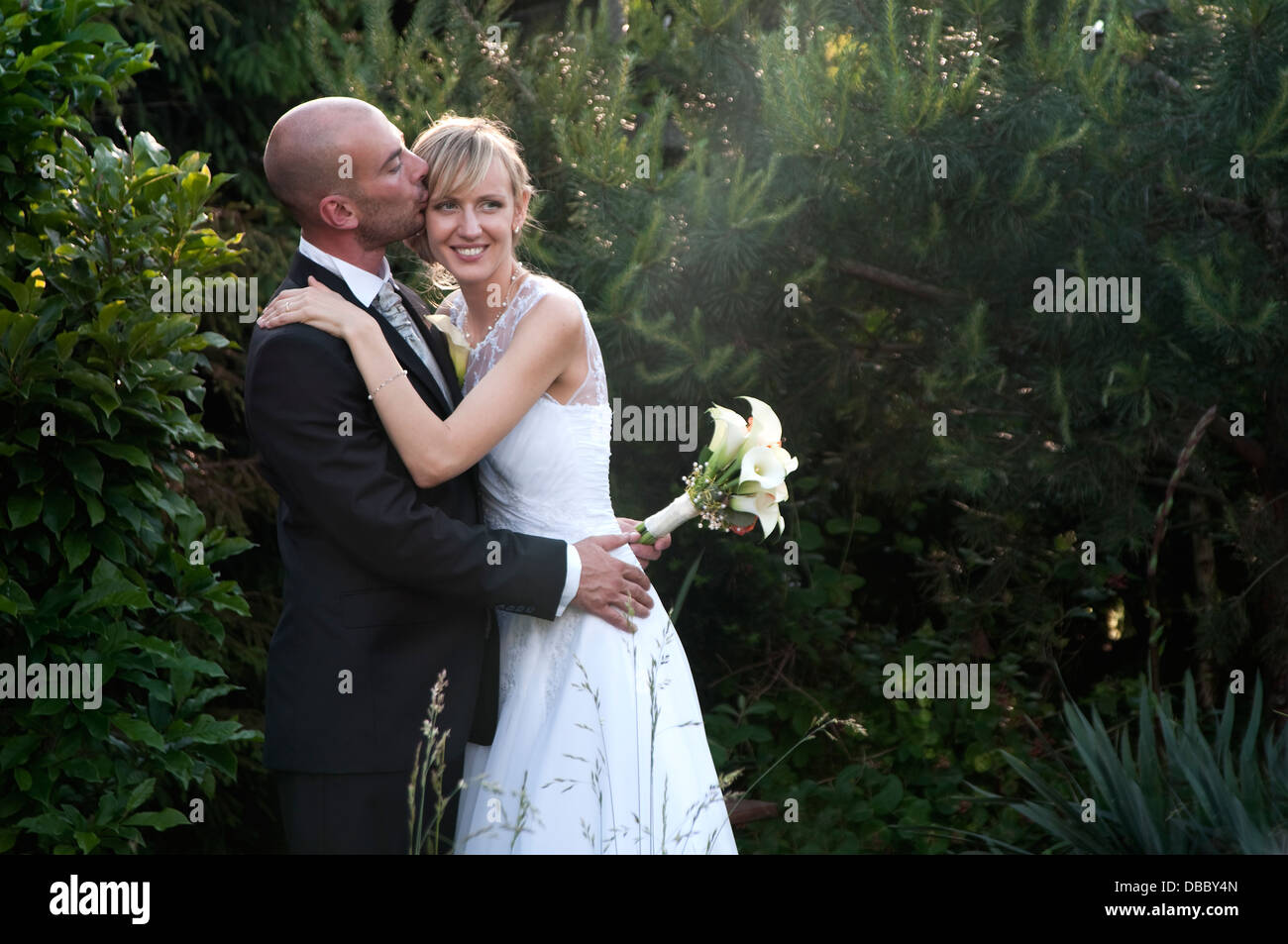 Bride and groom posing in the garden in the afternoon sun Stock Photo ...