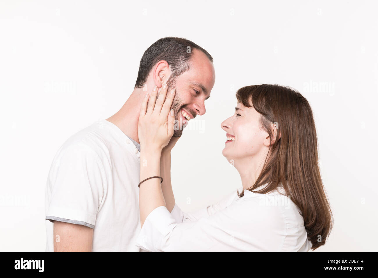 Loving adult couple looking at each other, woman holding man's face between her hands Stock Photo