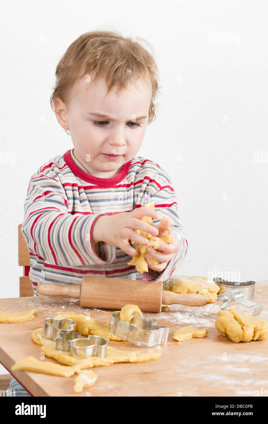 young child in vertical image looking at baking tools and working with