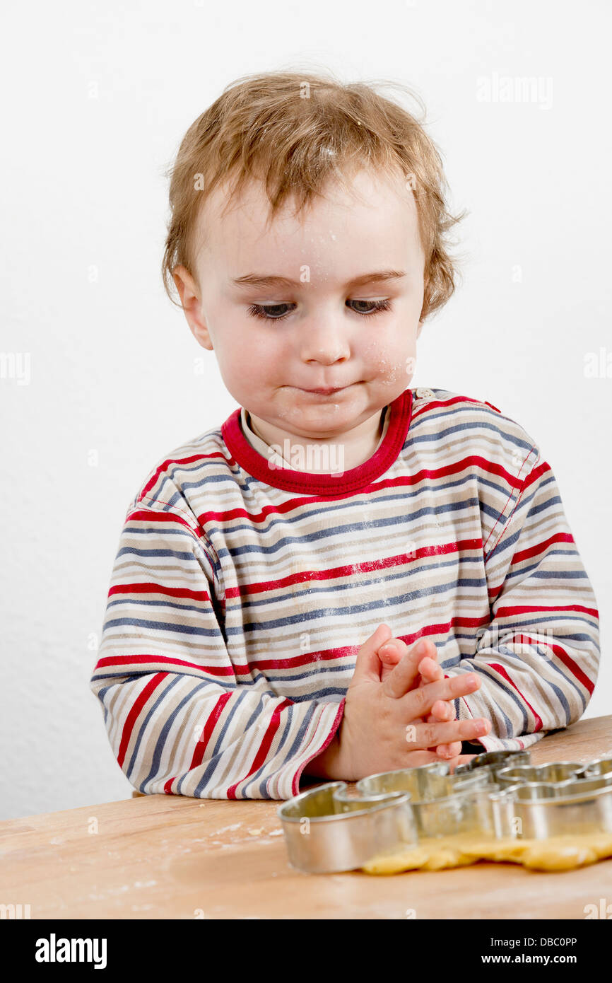young child in vertical image looking at baking tools and dough Stock