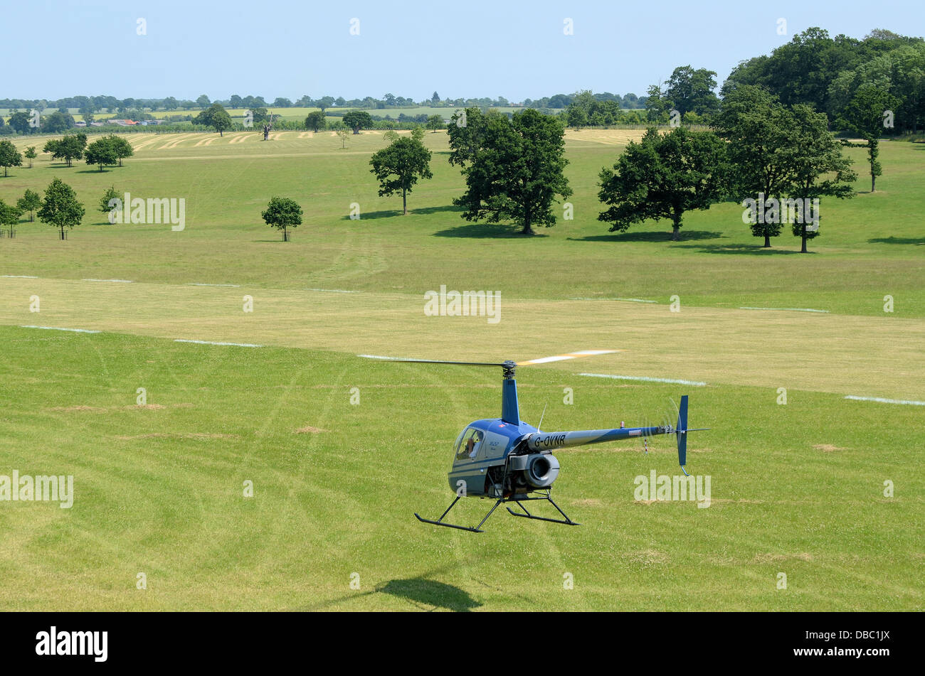 A Robinson R-22 helicopter flies through the beautiful British countryside at Heveningham Hall. Rural country in Suffolk Stock Photo