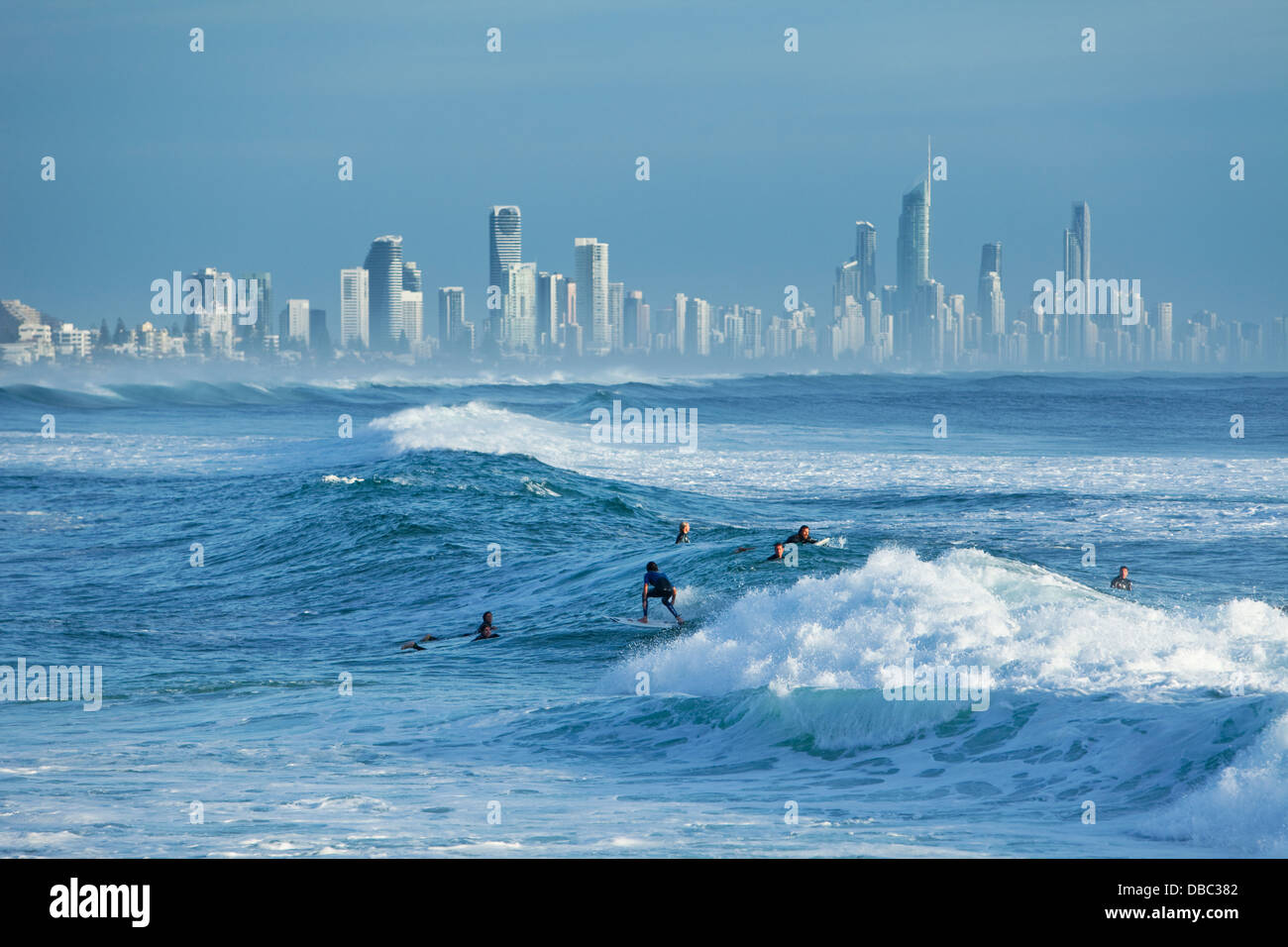 Surfer riding wave with Surfers Paradise skyline in background