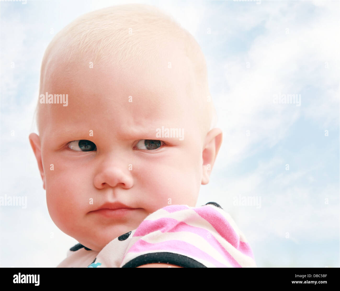 Funny baby girl outdoor summer close up portrait above cloudy sky Stock Photo