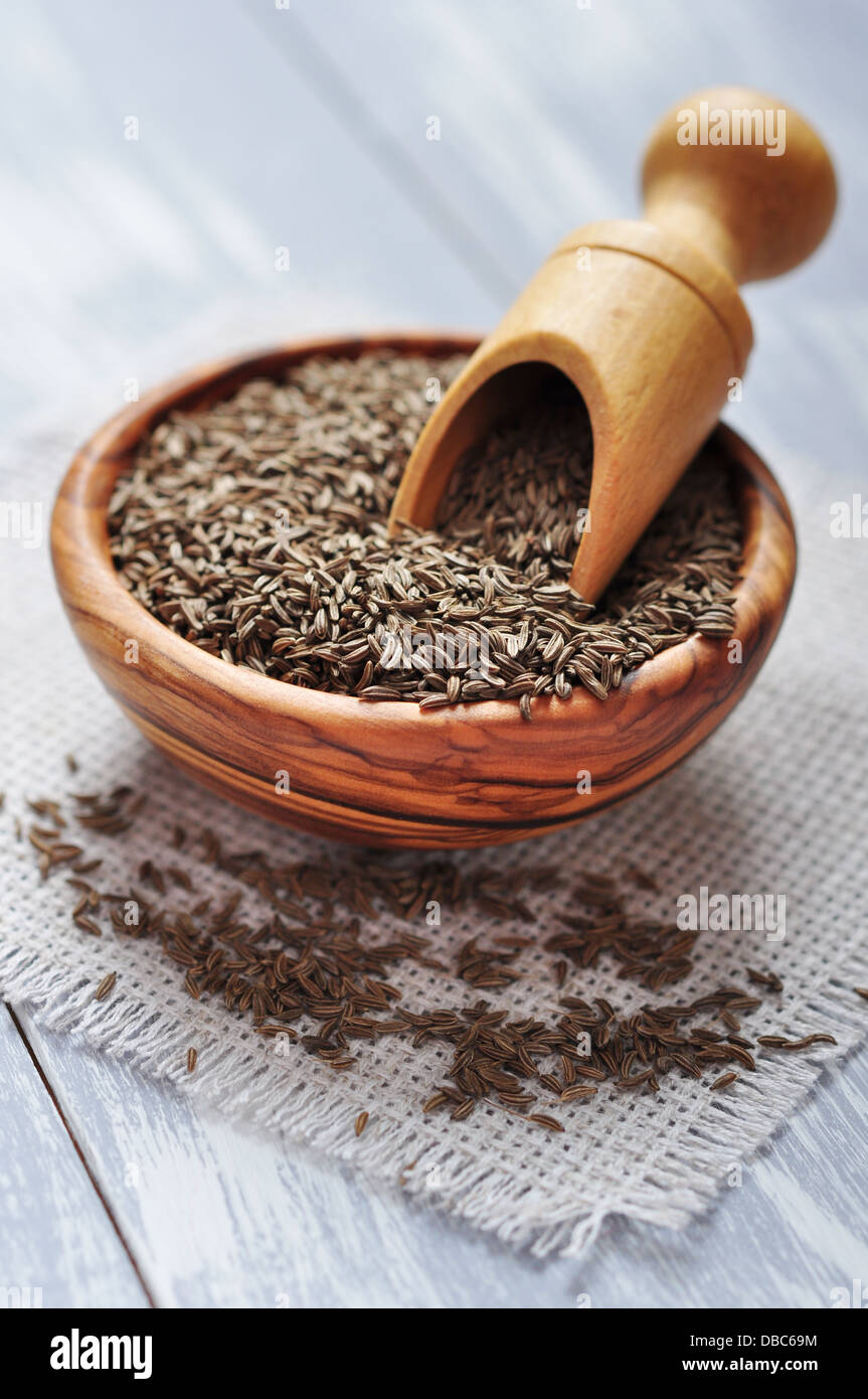 Cumin seeds in a wooden plate on wooden background Stock Photo