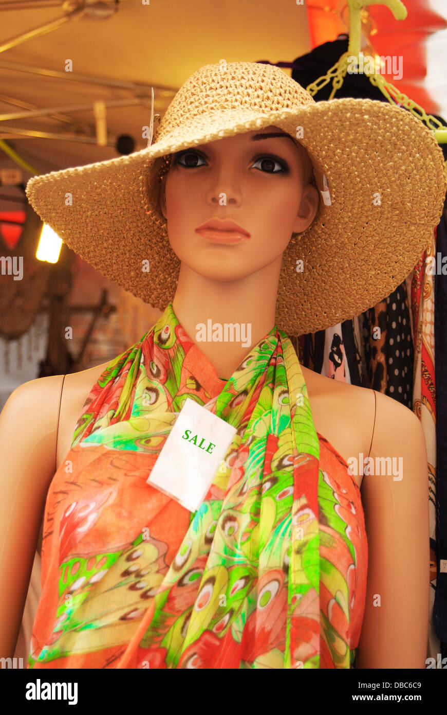 Woman mannequin dressed in a colourful summer dress and a straw hat with a sale sign Stock Photo