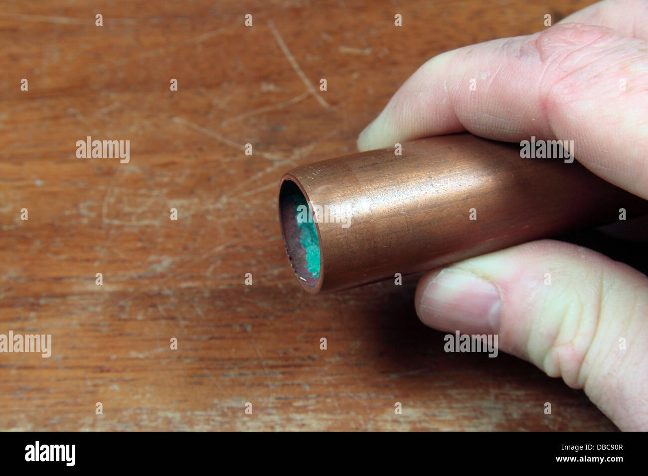 A man holding a small section of copper (Cu) piping, as used in a UK high school. Stock Photo