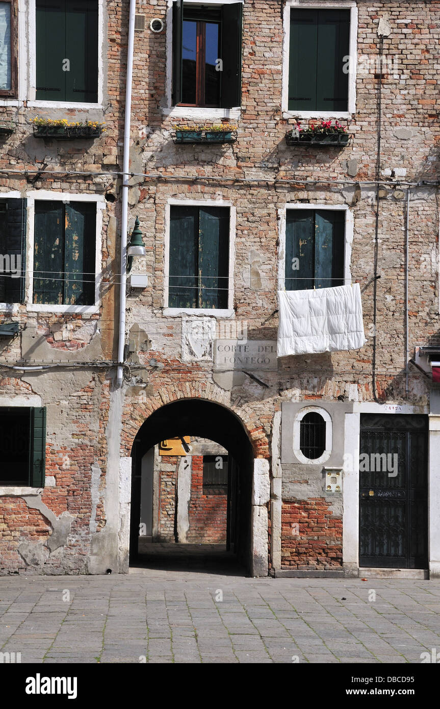 Typical old housing in Venice with duvet hanging outside on washing line in square - Italy Stock Photo