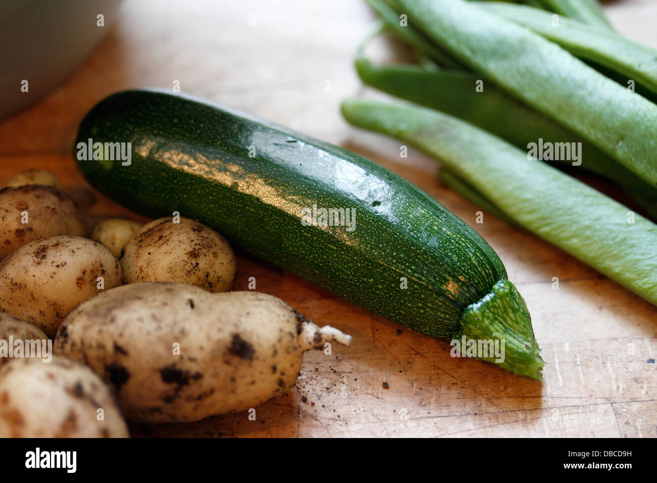 Picked and grown in the garden. l-r new potatoes - Solanum tuberosum, courgette or zucchini - Cucurbita pepo, runner beans - Phaseolus coccineus on a wooden (birch) kitchen worktop Stock Photo