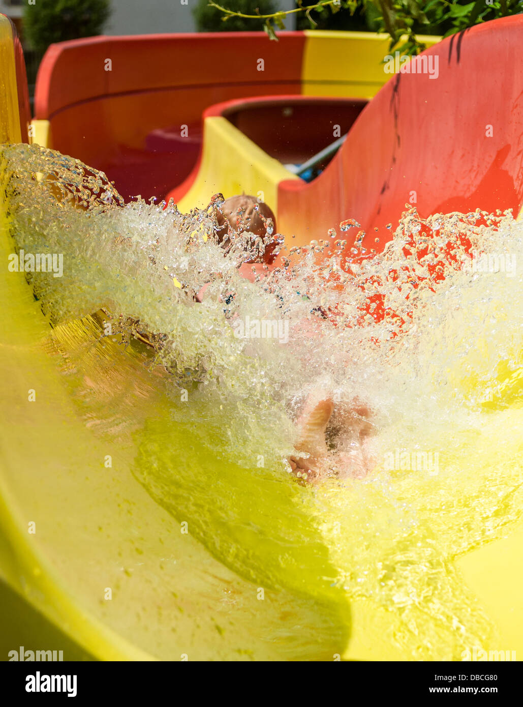 Young child having fun sliding down a waterslide Stock Photo