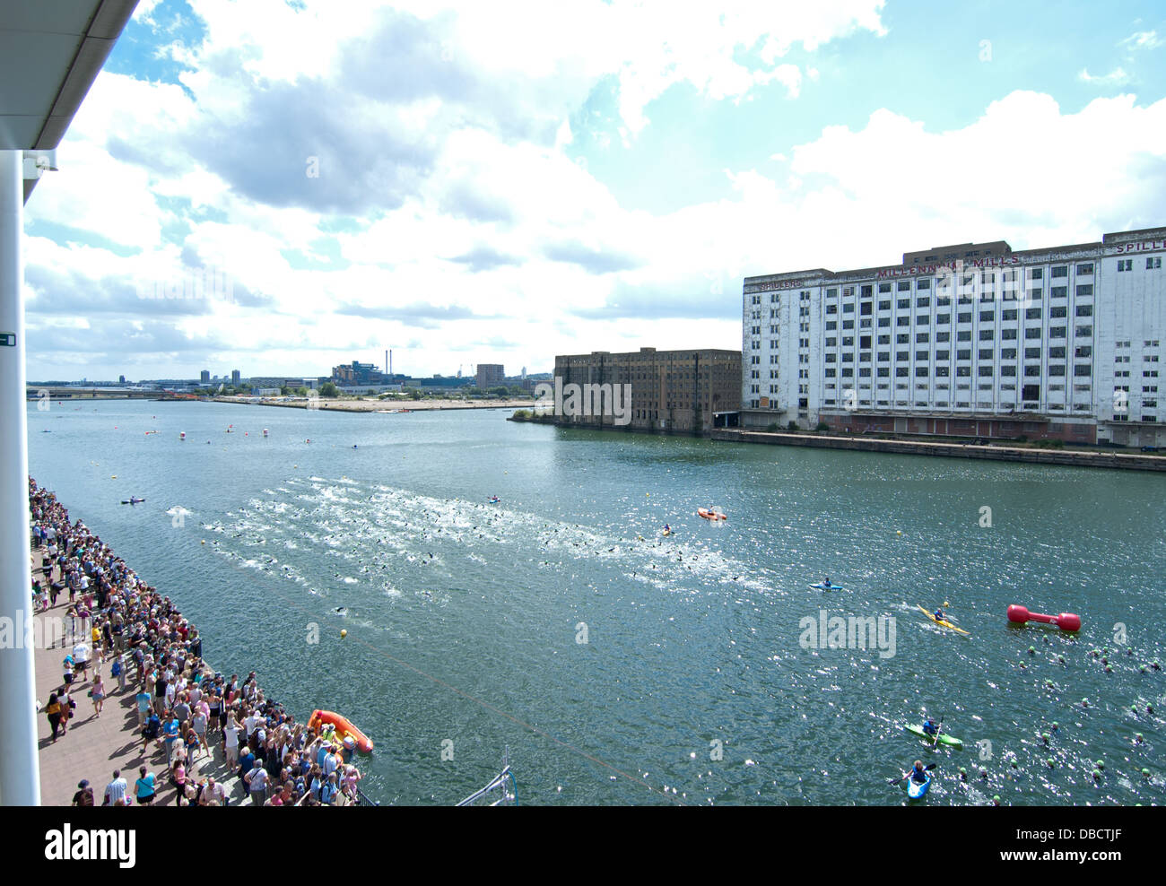 Dilapidated dockland building add a interesting backdrop as triathletes head off on their 1500km swim .2013 Virgin Active London Stock Photo