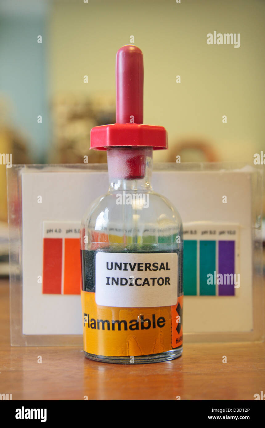 A small bottle of universal indicator with pH chart on a desk in a laboratory, as used in a UK high school. Stock Photo