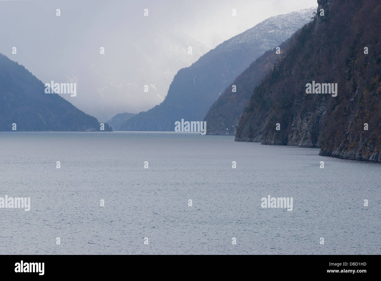Passing through the narrow Sunnylvs Fjord enroute to Geiranger Fjord on a frosty foggy mid-springtime morning Stock Photo