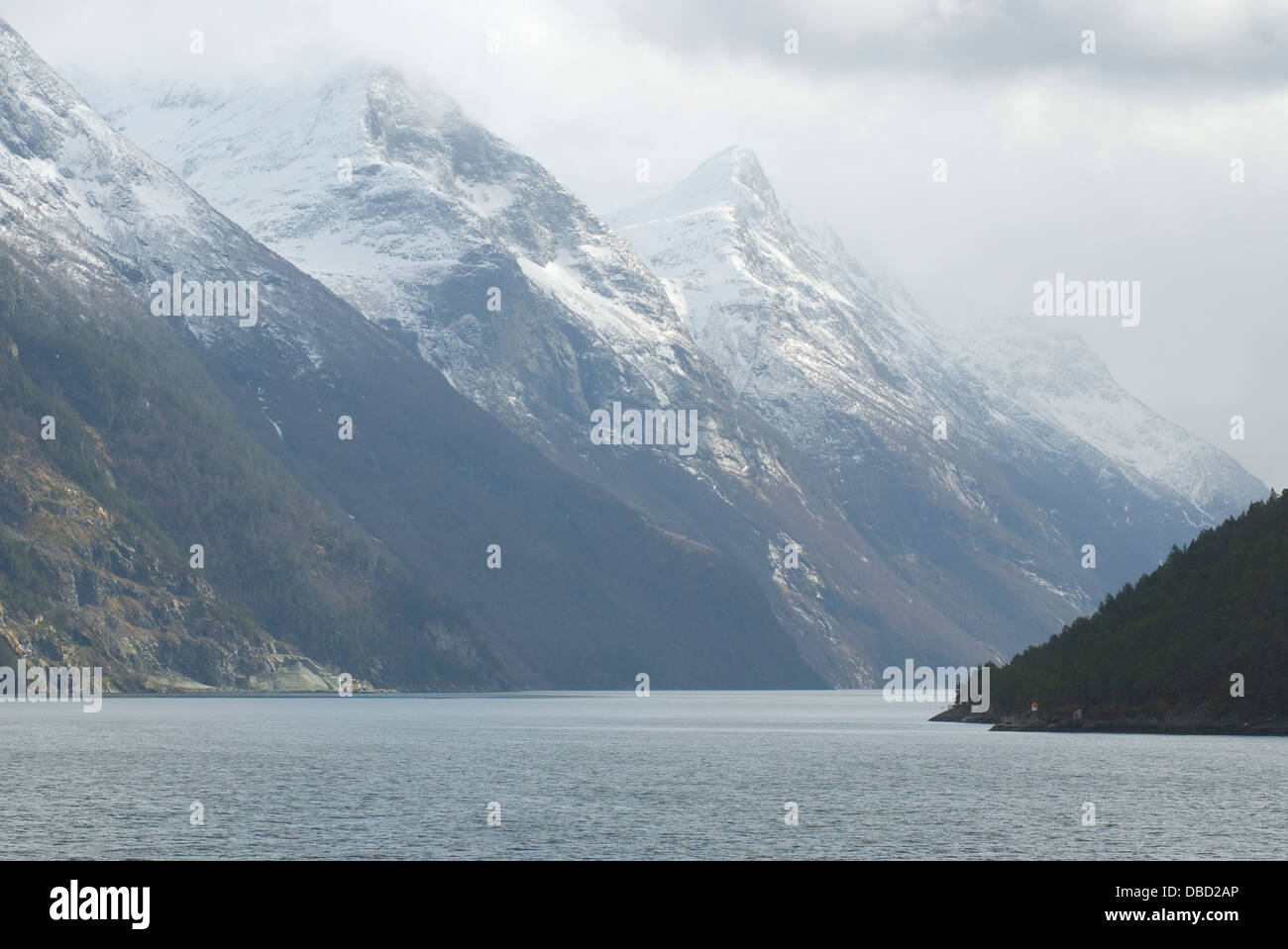Passing through the narrow Sunnylvs Fjord enroute to Geiranger Fjord on a frosty foggy mid-springtime morning Stock Photo