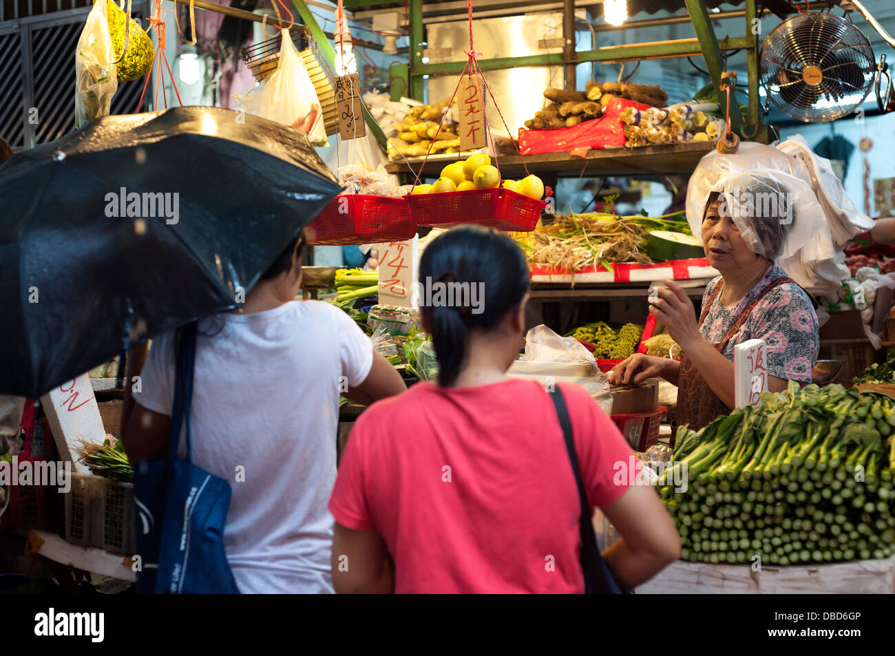 Woman wearing a plastic bag on her head at a rainy Graham Street wet market, Hong Kong Island Stock Photo